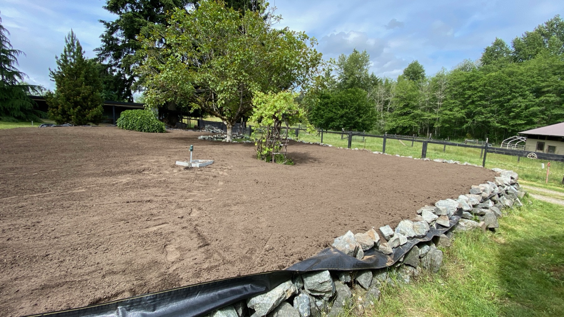 Freshly graded earth behind a newly built stone retaining wall